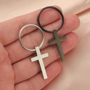 Sleek stainless steel cross keychains in silver and matte black on pink silk fabric
