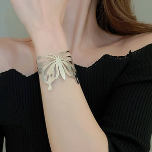 Detail of silver hollow butterfly cuff bracelet with flowing metallic liquid textures