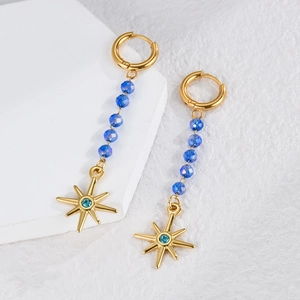 Elegant gold drop earrings with blue crystal beads and sunburst charm on a white stand