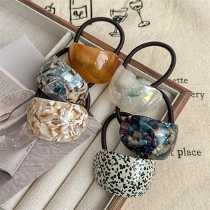 Elegant semi-circle hair ties with amber and marble patterns on a wooden tray