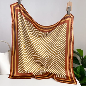 Détail d'un carré de soie satinée aux motifs géométriques dorés et bruns drapé sur un sac