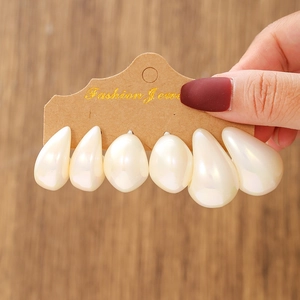 Close-up of set of 3 pairs drop-shaped pearl earrings on a brown display card