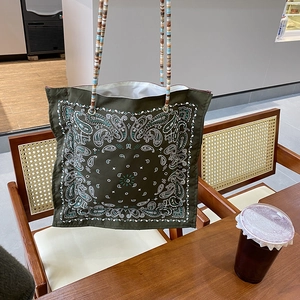 Boho military green paisley tote bag with colorful beaded shoulder strap in cafe setting