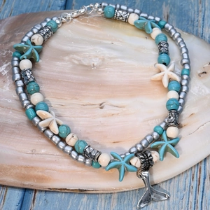 Detail of turquoise and starfish beads on double-layered silver anklet atop a shell