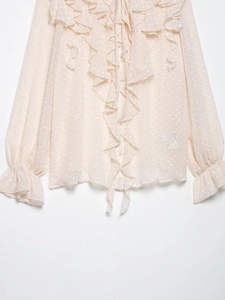 Close-up of beige chiffon blouse featuring ruffle trims and delicate polka dot patterns