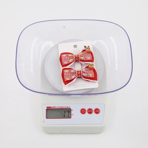 Detailed view of two red plaid Christmas bow hair clips weighed on a kitchen scale