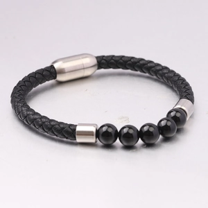 Dettaglio del bracciale in pelle intrecciata con occhio di tigre e chiusura magnetica