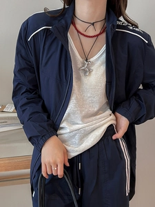 Detailed view of a silver balloon dog pendant necklace on a model in sporty outfit