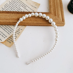 Detailed view of vintage faux pearl headband with gradient beads on a rustic background