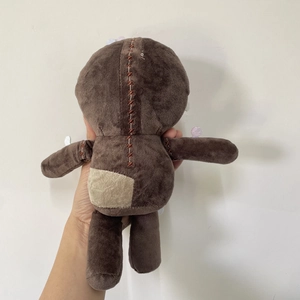 Stitched plush doll with dark brown fur and visible cross-stitch patch details on back