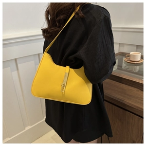 Detail of a bright yellow shoulder bag with a gold metal clasp buckle and smooth texture