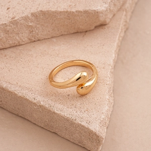 Macro detail of gold-plated water drop ring on stone showing mirror finish and texture