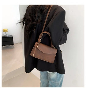 Détail du sac à bandoulière marron foncé avec poignée à nœud décoratif sur le mannequin