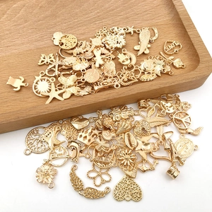 Macro shot of assorted golden alloy charms for DIY jewelry on a wooden tray
