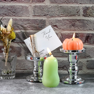 Arredamento accogliente con candele a forma di zucca e pera accese su candelieri argento