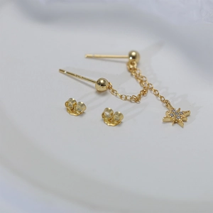 Detailed view of gold tassel earring chains with zircon star pendants and stud backs