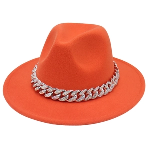 Detail of bright orange fedora hat with sparkling rhinestone Cuban chain decoration
