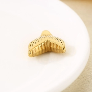 Detailed macro view of an 18k gold plated stainless steel mermaid tail pendant
