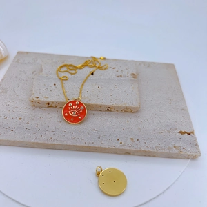 Detailed view of a gold-plated copper eye pendant with red enamel and sparkling star accents