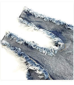 Makroaufnahme von blauem Denim mit destroyed Details und ausgefransten Kanten