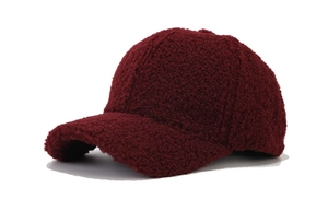 Close-up of wine red lamb wool baseball cap texture with detailed grainy plush finish