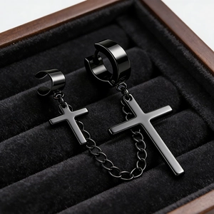 Detail of black stainless steel cross earring with chain and ear cuff on velvet