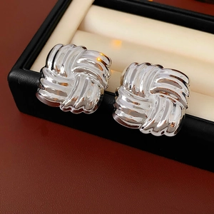 Macro shot of silver square woven texture earrings on black leather jewelry box