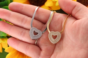 Macro shot of gold and silver heart pendants with micro-inlaid zircons on snake chains