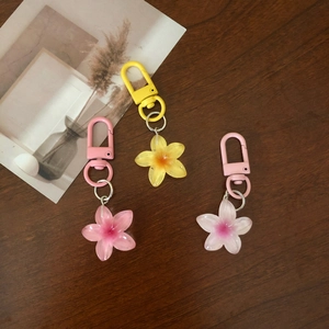 Colorful floral resin keychains in pink, yellow, and white on a natural wood surface