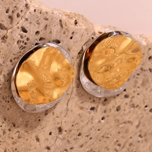 Macro detail of bicolor gold and silver irregular earrings with hammered metal texture