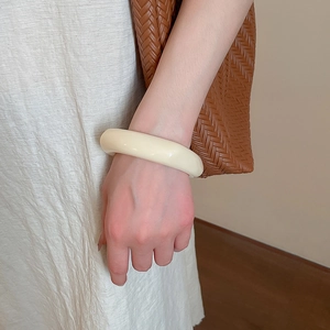 Detailed view of thick cream acrylic geometric bracelet worn with a casual outfit