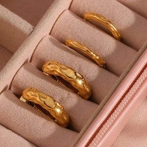 Detailed close-up of golden irregular hammered texture earrings in a pink velvet box