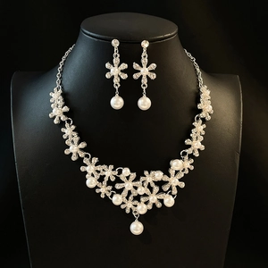 Elegant floral pearl necklace and earring set with crystals on a black bust display