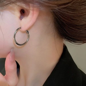 Close-up of a minimalist silver hoop earring on model with polished metallic finish