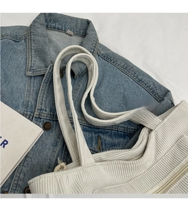 Detail of soft corduroy fabric texture and durable handle on beige shoulder bag