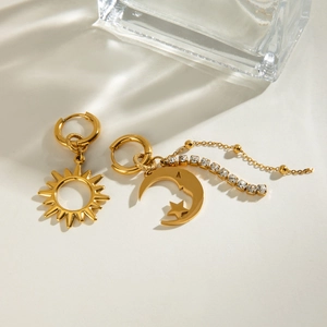 Macro shot of gold sun and moon earrings with white rhinestones and dangling chain