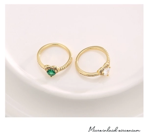 Detail of micro-inlaid heart rings with pink and green zircon on a ceramic tray