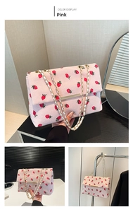 Close-up of pink corduroy strawberry print bag with gold chain and metal bar detail