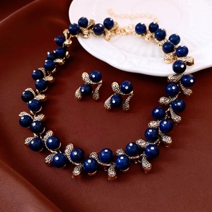 Detailed view of vintage gold leaf jewelry set with deep blue beads on silk fabric