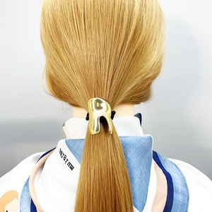 Minimalist gold metal curved ponytail holder with elastic hair tie shown on a blonde model