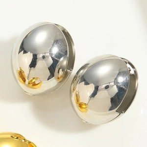 Macro shot of minimalist polished gold and silver spherical earrings on a white backdrop