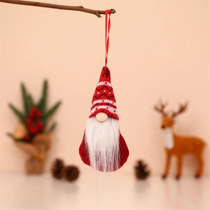 Detail of red knitted gnome ornament with long white beard hanging on festive wood branch