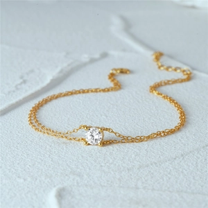 Detailed view of dual-layer gold-plated chain with four-prong set sparkling zircon