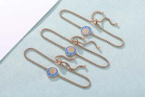 Dettaglio di bracciali zodiacali in oro rosa con chiusura regolabile e smalto blu