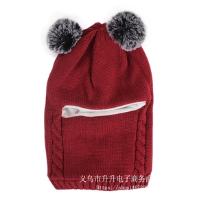 Detail of red knitted winter hat with dual faux fur pom-poms and warm sherpa lining