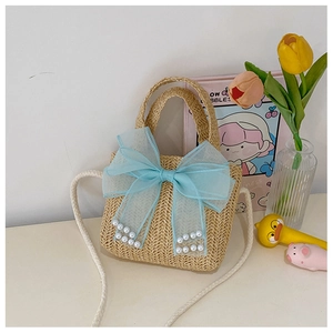 Detail of hand-woven straw bag featuring blue mesh bow and white pearl accents
