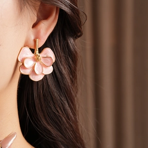 Macro detail of pink ginkgo leaf flower earring with gold trim on model ear