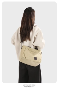 Detailed back view of a khaki canvas messenger bag with a brown shoulder strap