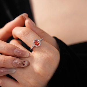 Macro shot of a silver ring featuring an oval orange gemstone surrounded by white zircons