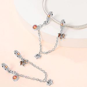 Detailed view of silver safety chain charms with orange gems and autumn maple leaf pendants
